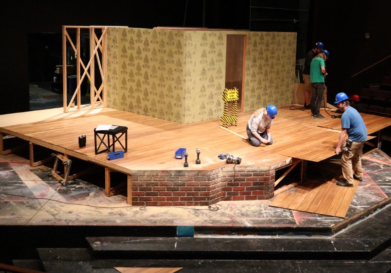 a crew of people setting up the set of Brighton Beach on the stage