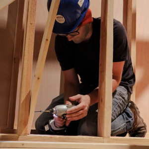 Man drilling a nail into a piece of plywood