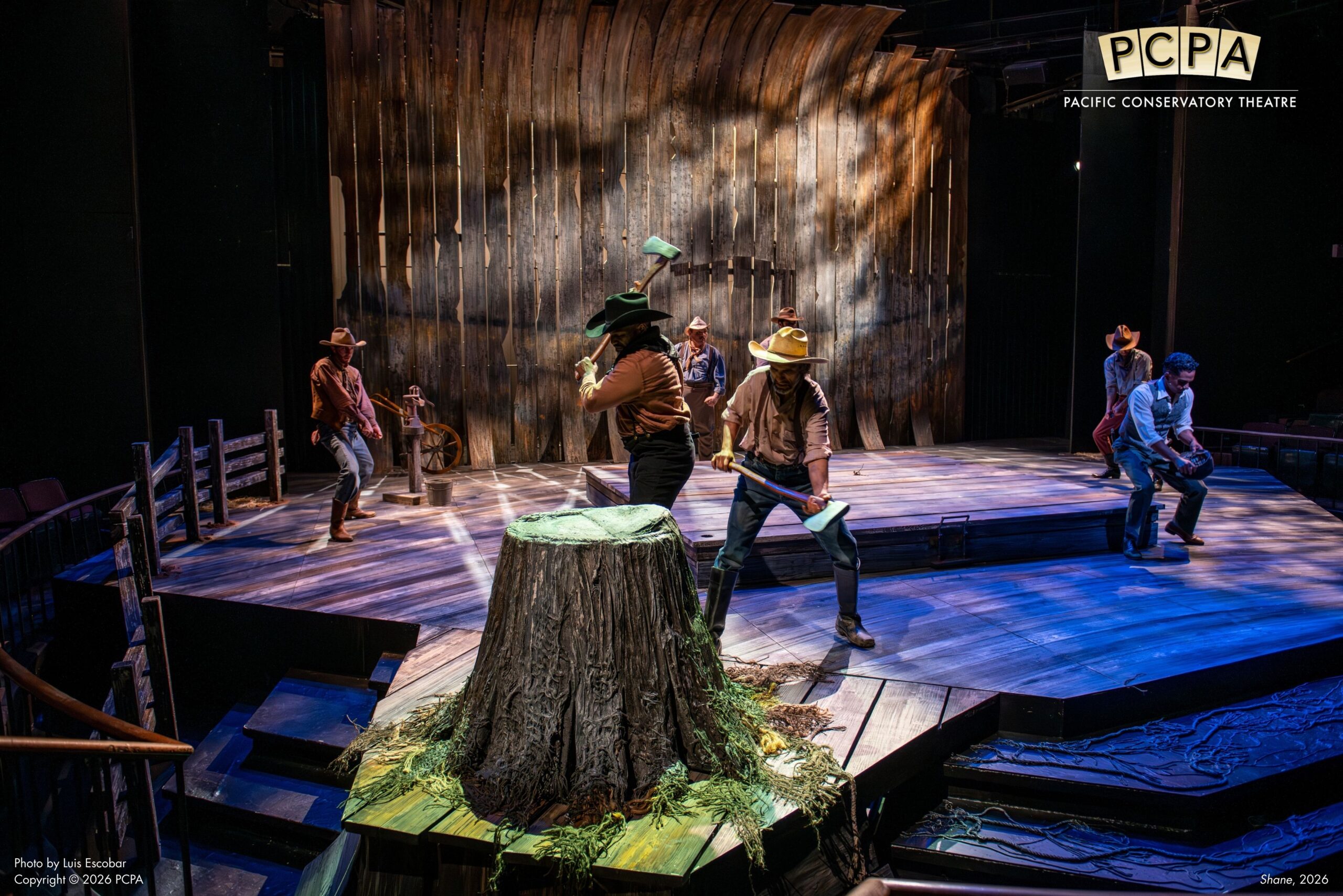 Actors on stage cutting down tree stump