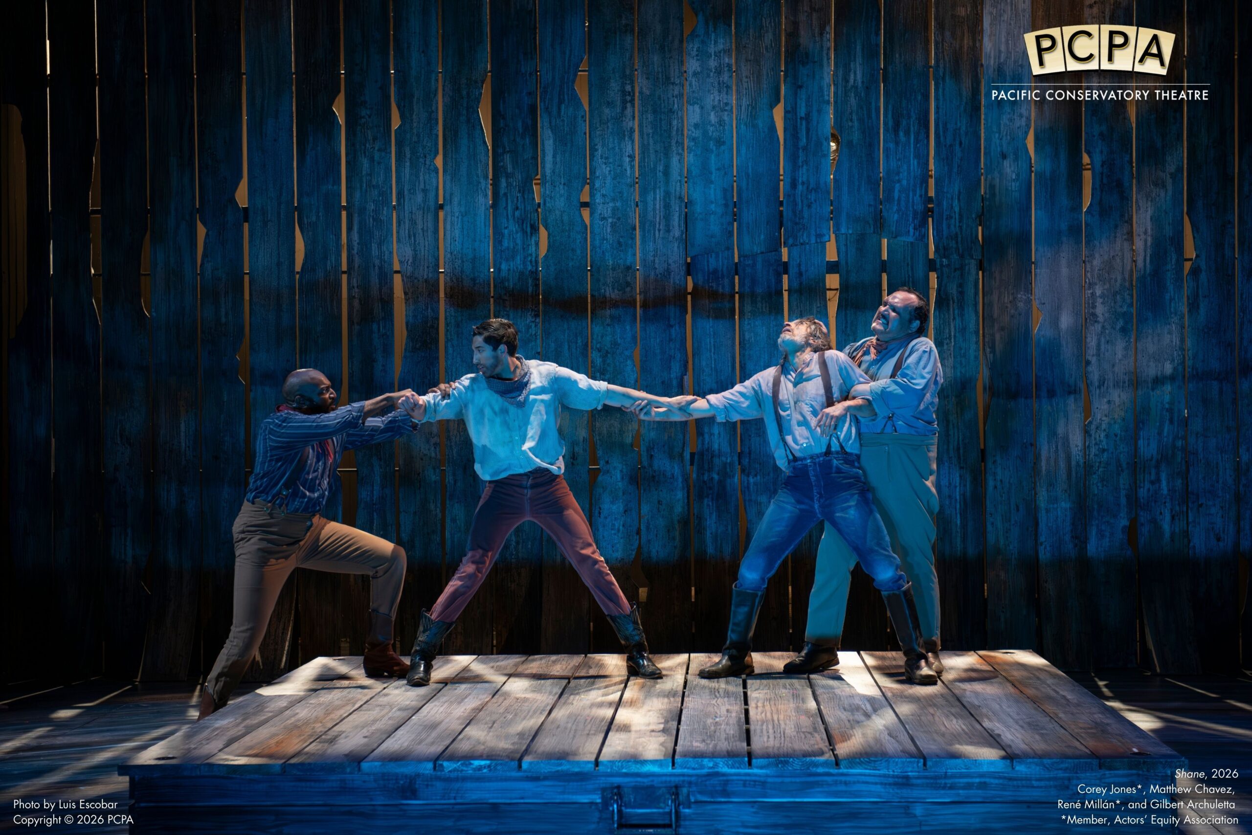 Actors standing on stage pulling each other from the arms