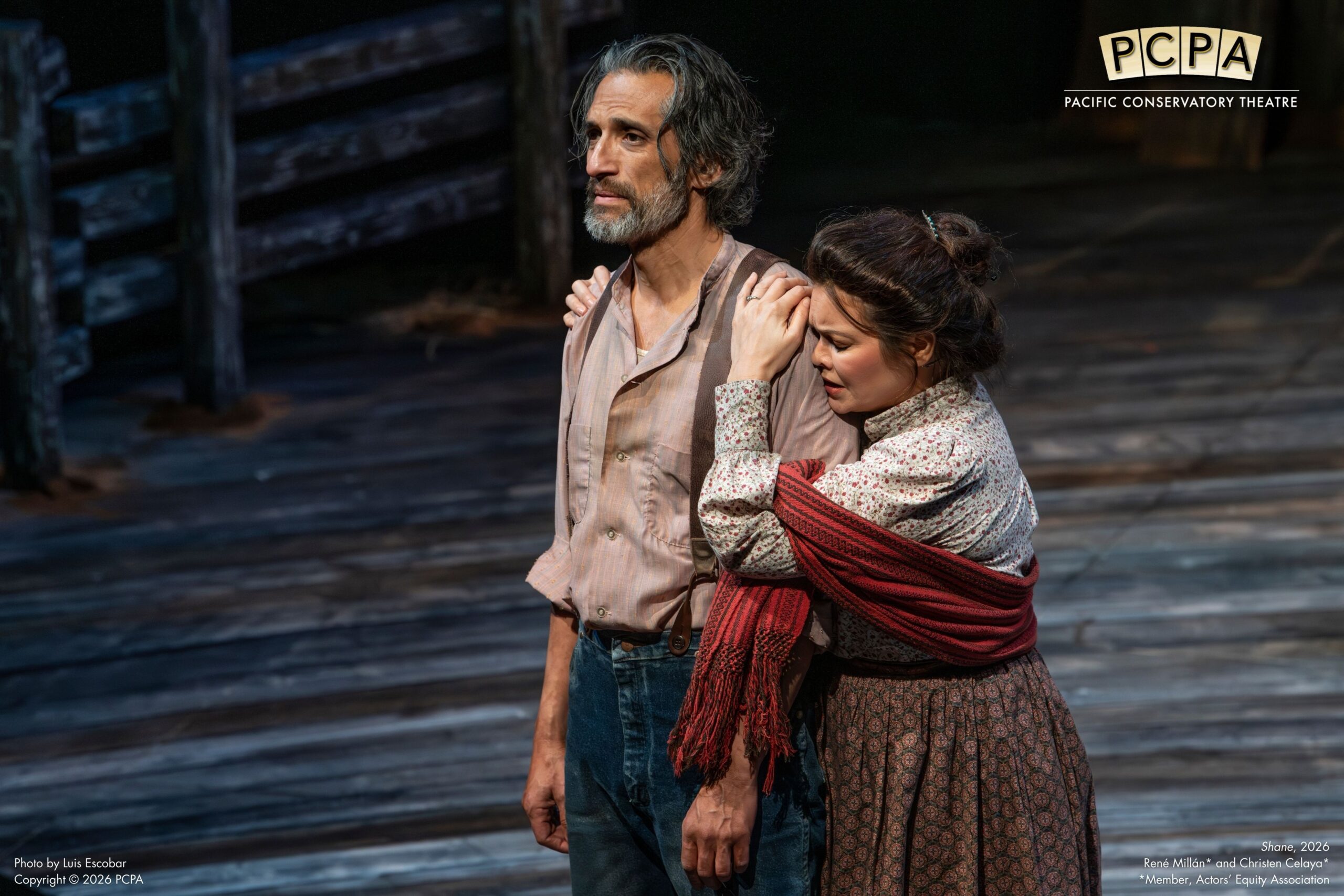 Actor standing on stage while woman hugs him from the side