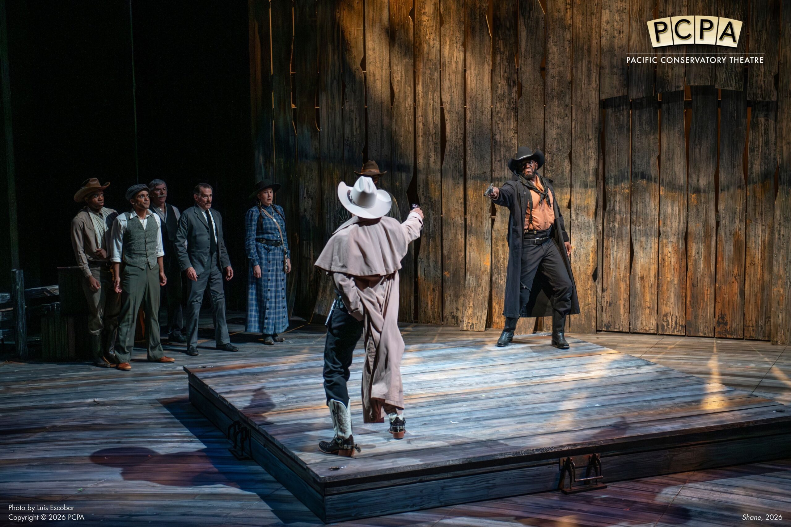 Actors standing on platform with guns drawn to each other