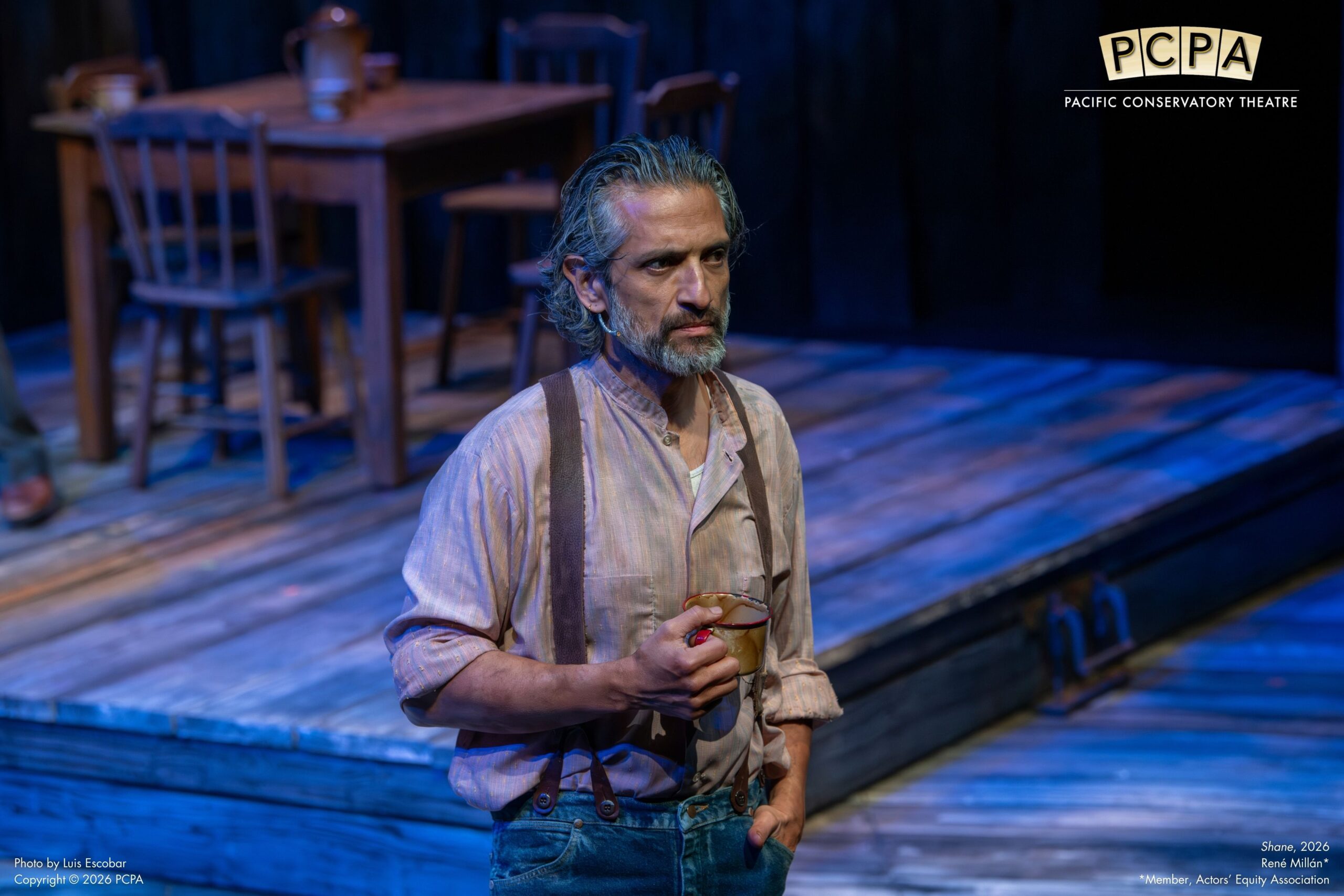 Man holding mug looking off stage